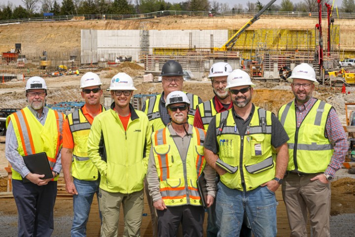 Representatives from OSHA’s Omaha Area Office, Sampson Construction and the Nebraska Onsite Safety and Health Consultation Program stand in front of the construction project’s  underground retaining wall in the far background. 