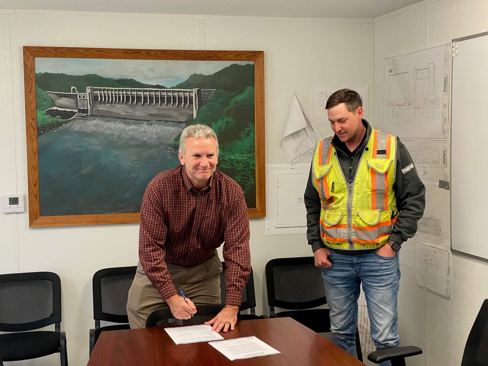 In an office setting, Blake McEnany, OSHA, and Logan Hamilton, Brayman Construction Corporation, sign the Partnership agreement.