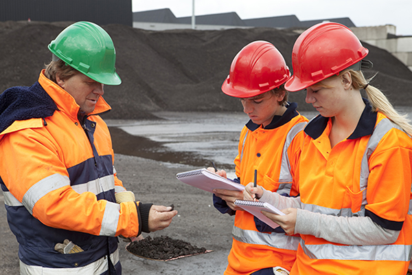 An adult foreman is guiding a male and a female youth workers