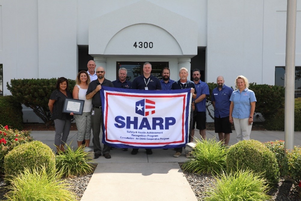  Representatives from Western Aircraft and Boise State University Office of Safety and Health Consultation with the SHARP flag during the recognition presentation.