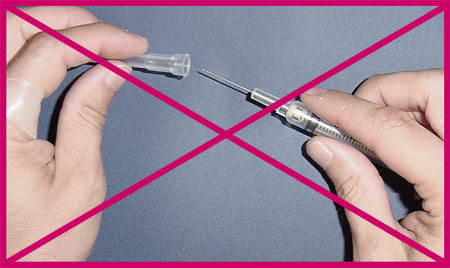 Example of unsafe sharps handling: close up of uncovered hands removing needle cap