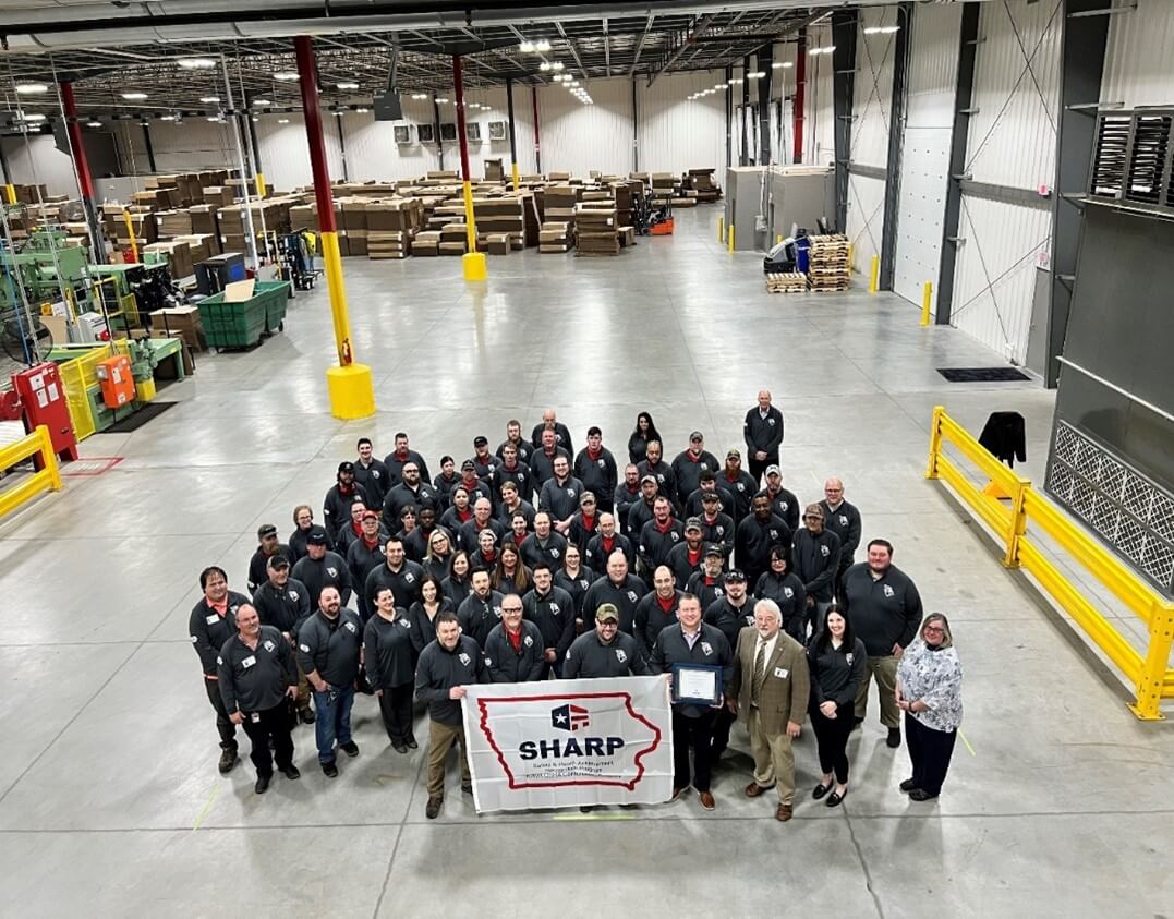 Employees and management standing with the SHARP flag