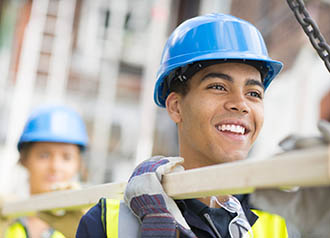 Construction - two young workers carring a board. | Copyrighted:sturti - iStock.com:513392547