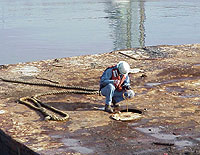 Figure 3: Shipyard Competent Person, with PFD, testing tanks on a barge prior to authorizing entry. Note: Fall protection to be installed after testing for initial entry.