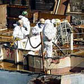 Figure 1: Workers using suction hose for removing residue from below deck