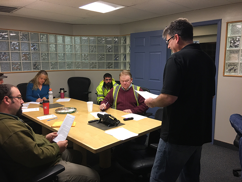 Pro Recycling staff at a weekly safety meeting. Mike Shaw - Director of Safety (Speaking), Todd Smith -Driver (to the right), Jonny Attwood - Driver (right and back), Beth Peck - Dispatch (center back), Bryan Rasmussen - Driver (left back), Beau Peck - Director of Sales and Marketing (left front)" title="Pro Recycling staff at a weekly safety meeting. Mike Shaw - Director of Safety (Speaking), Todd Smith -Driver (to the right), Jonny Attwood - Driver (right and back), Beth Peck - Dispatch (center back), Bryan Rasmussen - Driver (left back), Beau Peck - Director of Sales and Marketing (left front)