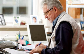 Worker at a desk with a computer screen near him - Photo Credit: OSHA/OOC - https://www.osha.gov/silica/factsheets/OSHA_FS-3685_Silica_Small_Biz.html
