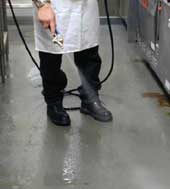 restaurant worker washing down the floor with a spray nozzle hose
