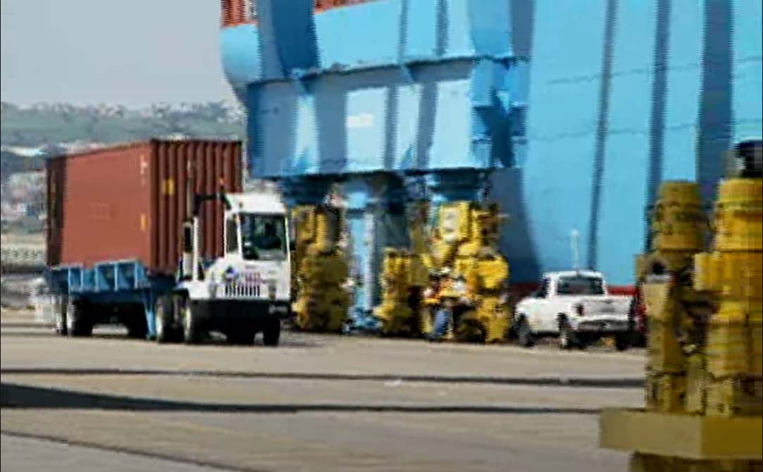Tractor trailer truck driving past a docked ship