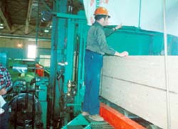 A worker bands and wraps a lumber package.