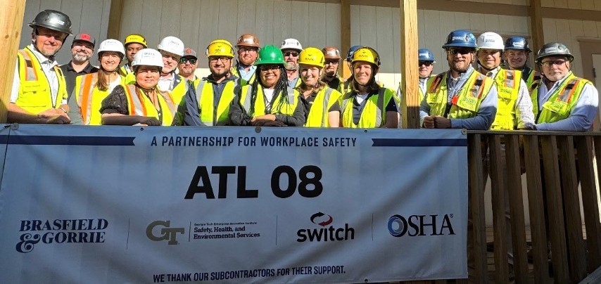 With the construction project’s Partnership banner in the foreground, representatives from OSHA, Georgia On-Site Consultation and Brasfield & Gorrie, LLC, stand behind the banner at the worksite.