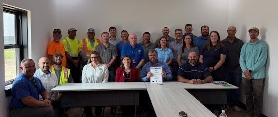 In a small office, attendees to the Partnership signing ceremony pose for a group photo, after the agreement was signed