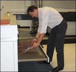 Figure 7. Awkward bending to place plates into drawers of processing unit to dry.