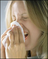 Woman sneezing into a tissue