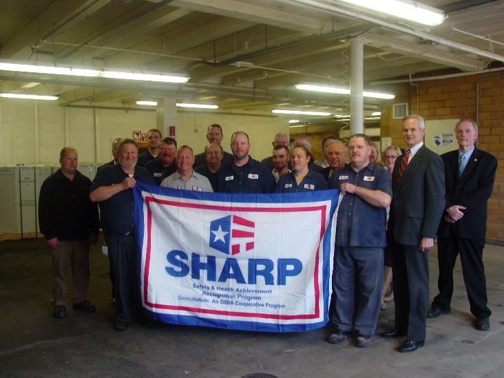 Company employees in front row with Lt. Governor Mike Foley, Eldon Diedrichs, Consultation Manager, Commissioner, John Albin, Safety Director, Christopher Cantrell, Mayor, Homer ward, Company representatives, Michelle Engel, Safety, Ron Schacht, Manager, Denise Schacht, Nick Schacht, Manager John Korthals, Safety and Scott Carlson-CEO