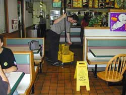young worker mopping a floor in a restaurant