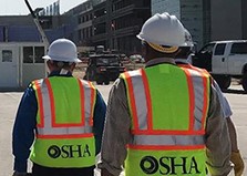 Workers wearing hard hats and high-viz vests walking across job site