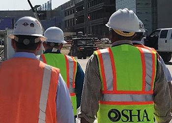 Trabajadores que usan EPP mientras caminan por el sitio de construcción