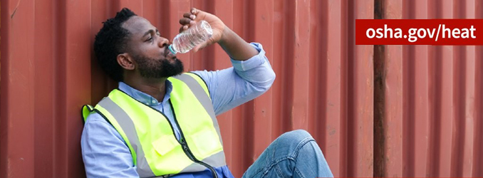 Worker in high-viz vest taking a break to sit down and drink water while working outside in the heat