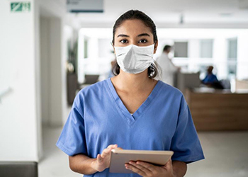Trabajador del hospital con máscara y trabajando en tableta