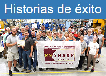 Los empleados de Gemini Inc. se paran en su taller, sosteniendo con orgullo su bandera SHARP