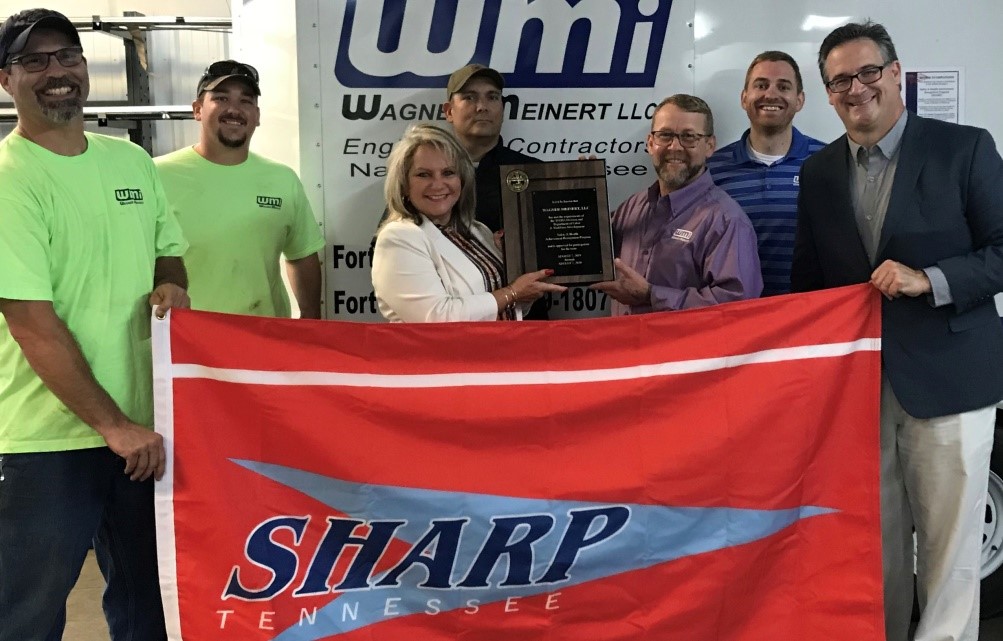 TOSHA Assistant Commissioner Wendy Fisher (center) presents the TOSHA SHARP flag to the employees and management of Wagner-Meinert LLC in Nashville, Tennessee